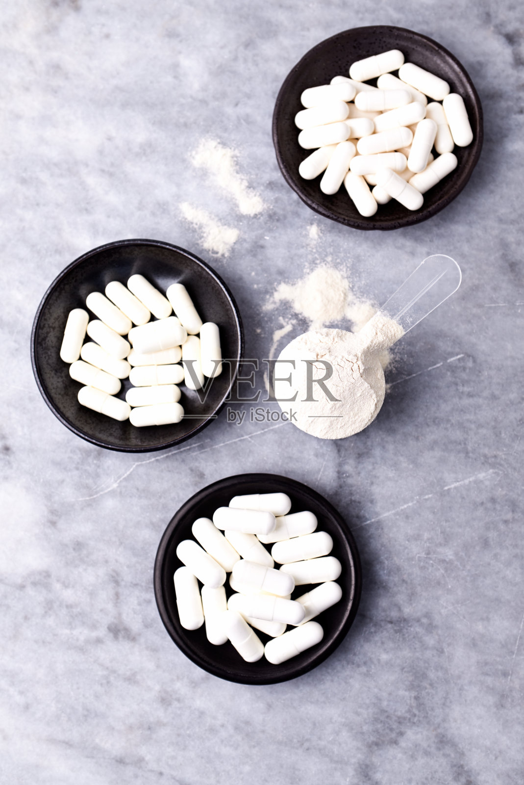 乳清蛋白,水解膠原I型,l -脯氨酸和l -賴氨酸膠囊勺。補充膠原蛋白的生產(chǎn)。明亮的石頭背景。直接上圖。副本的空間。